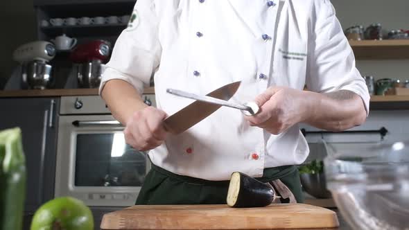 chef in modern kitchen of restaurant sharpens a knife for cutting vegetables. alt