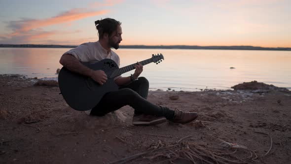 Silhouette of a Young Man on the Beach with a Guitar Playing Chords By Torrevieja Pink Lake in alt