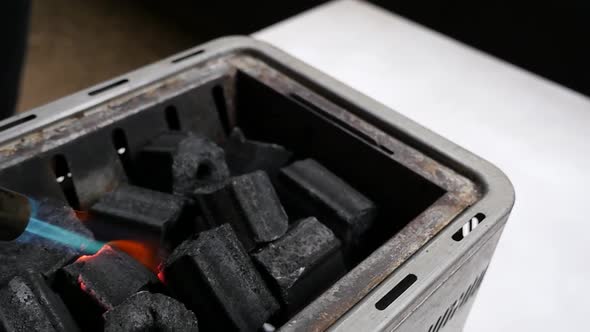Fresh black charcoal starting to get lit on fire in hibachi grill