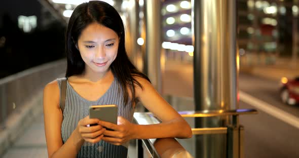 Woman looking at mobile phone in the city at night  alt