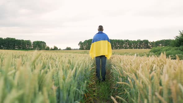 A Ukrainian Farmer Stands in the Middle of a Field of Golden Wheat with the Flag of Ukraine