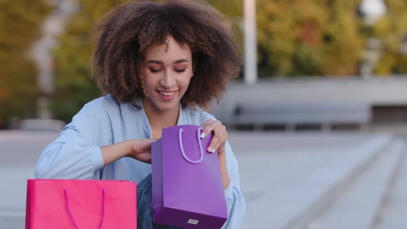 Curious Satisfied Afro American Woman African Curly Girl Buyer Sitting Outdoors Looking Insode in alt