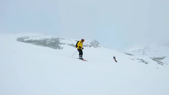 Man in yellow jacket ski's down a mountain on a cloudy day in Laax, Switzerland alt