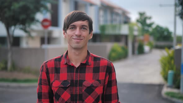 Portrait of Handsome Caucasian Man in Red Plaid Shirt Standing in Front of the Camera and Smiling at