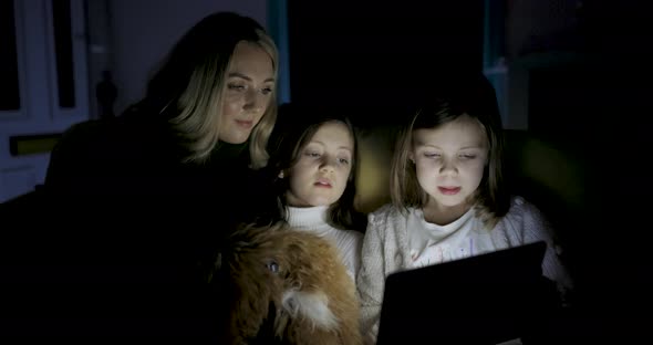 Woman and two girls using digital tablet at home to read ebook and remote lea
