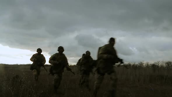 Silhouettes of Soldiers Running Across the Field