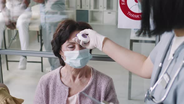 Senior Woman Measuring Temperature At Hospital alt
