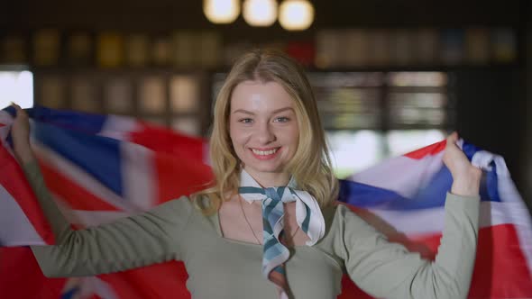 Portrait of Excited Beautiful Woman with British Flag Rejoicing Looking at Camera Smiling alt