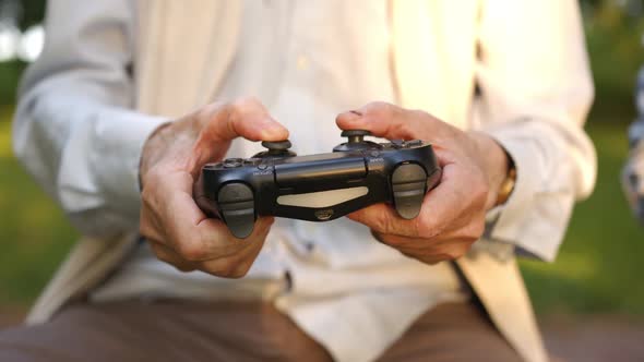 An Old Men Holds a Joystick in His Hands and Play Game alt