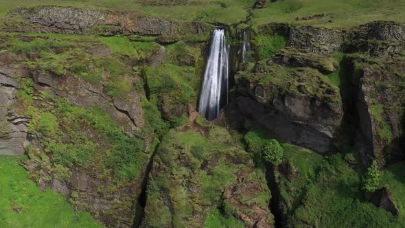 Small waterfall in Iceland with drone video pulling out to wide shot. alt