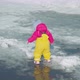 Toddler runs through puddles melting snow in a yellow rubber jumpsuit. Top view - VideoHive Item for Sale