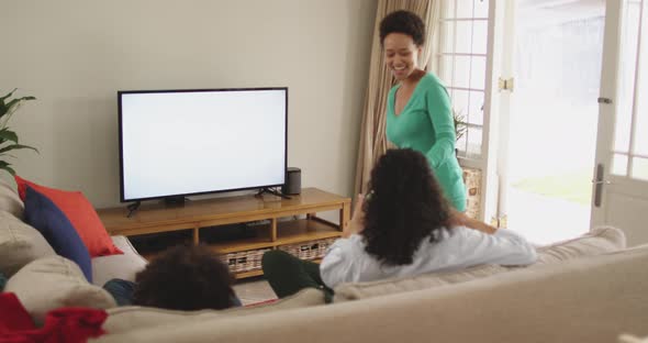 Mixed race lesbian couple and daughter watching tv sitting on couch, Stock Footage