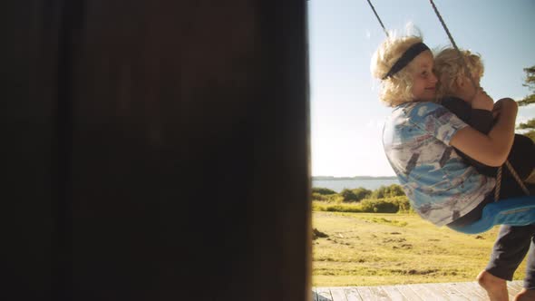 Young Brothers Sitting On Swing alt