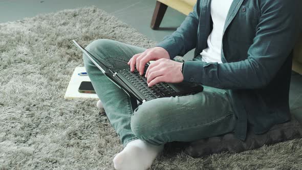 Man Working at the Computer with a Lot of Reminder Notes Sitting Near Sofa alt