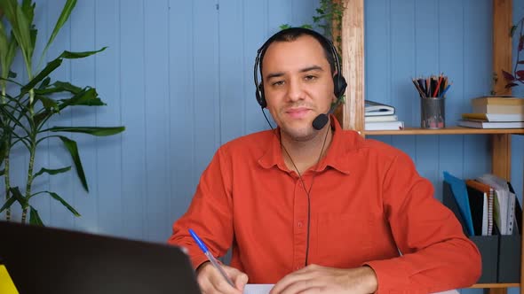 Portrait of Happy Young Businessman Sitting at Table in Home Office and Working at Laptop alt