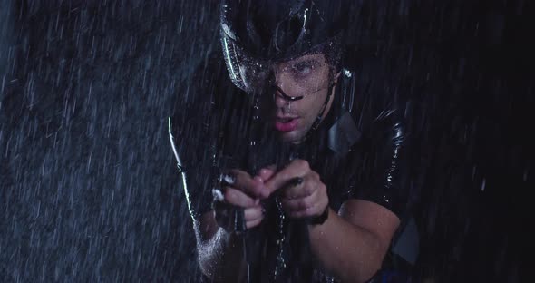 Triathlon Athlete Riding a Professional Racing Bicycle on an Intense Workout in Dark with Rain alt
