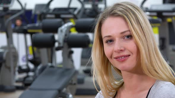 A Young Beautiful Woman Smiles at the Camera in a Gym alt