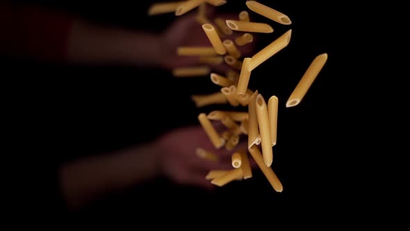 Person Hand Throws Upward Raw Yellow Penne Pasta Macro alt