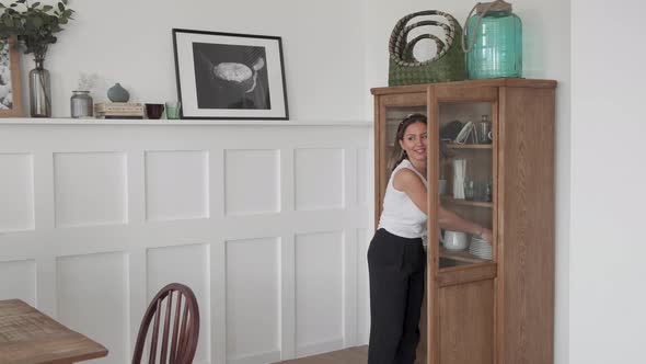 Lockdown of young Caucasian woman wearing casual clothes putting four white plates alt