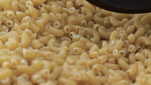 Wooden Spoon Scooping Elbow Pasta