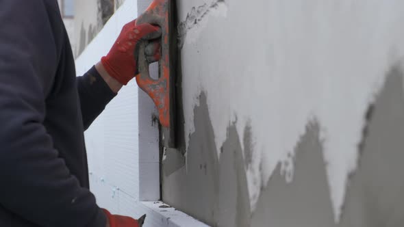 Construction Worker Covering House Wall with Adhesive Cement Glue Berore Installing Styrofoam alt