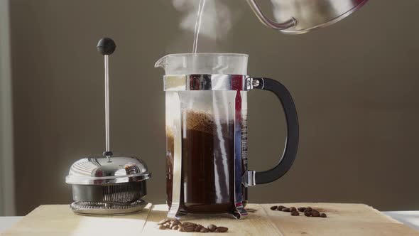 Unrecognizable person pouring water from coffee kettle into French press alt