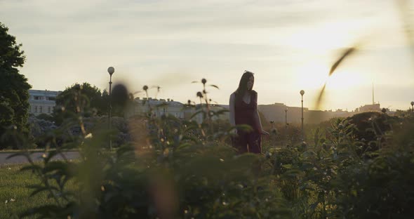 Young Beautiful Girl Dancing in the City Against the Backdrop of the Sunset Sky alt