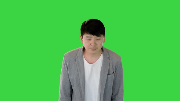 Young Asian Man in Casual Clothes Makes a Bow on a Green Screen Chroma Key
