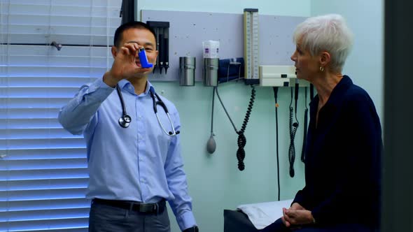 Young Asian male doctor and senior patient discussing over asthma inhaler at clinic 4k alt