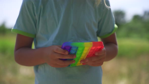 Blonde Boy Plays Popit Rainbow Colors in the Park
