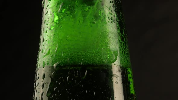 Drop of condensation drips on beer bottle glass. Water drops falling down alt