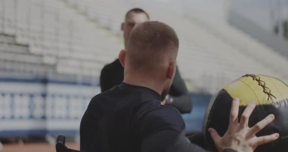 Wheelchaired Athlete and Trainer Throwing Medicine Ball alt
