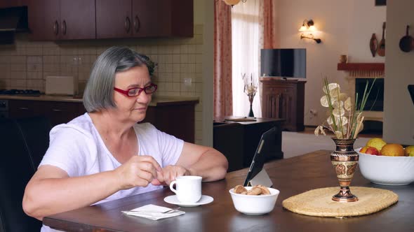 Senior Woman with Coffee Using Digital Tablet Pc