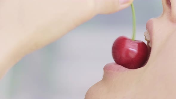 Macro of a Caucasian Young Girl is Eating One Whole Red and Ripe Wild Cherry