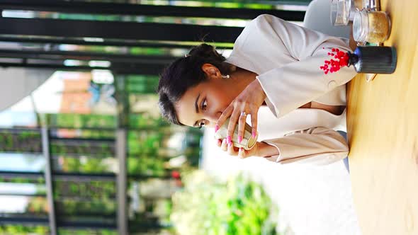 Young Business Woman Holding and Drinking Coffee in Street Cafe in City alt