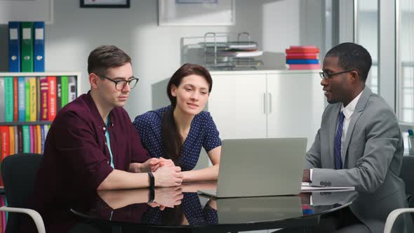 AfricanAmerican Broker Advising Young Couple Showing Investment Strategy on Laptop alt