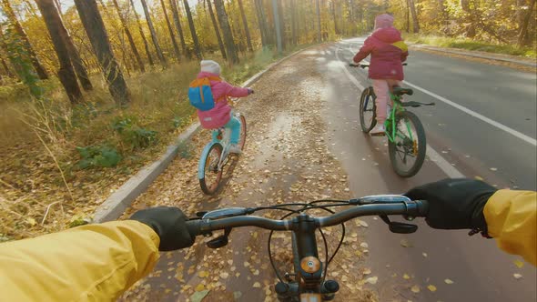 Father with Her Daughters Have a Bike Ride in Autumn Park POV View alt