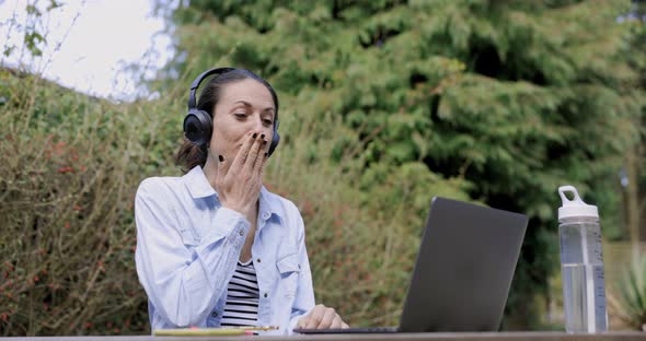 Woman with headphones ending video call with blow kiss