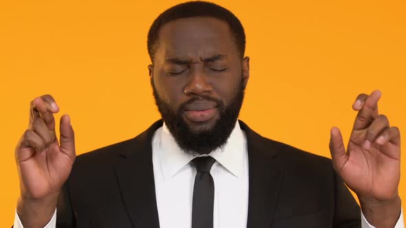 Black Male in Suit Crossing Fingers for Good Luck, Hoping to Win, Faith in Best alt