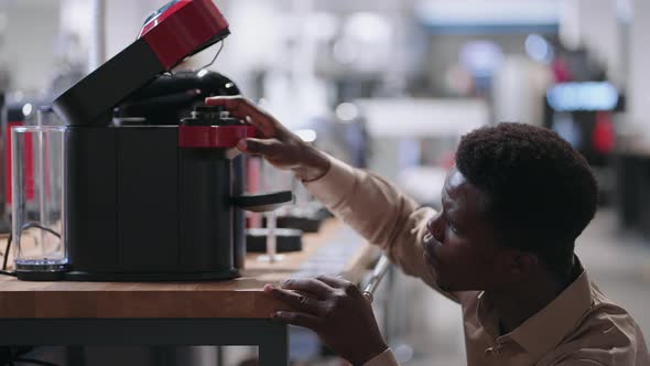 Man is Viewing Modern Coffee Machine in Home Appliance Store Young Black Guy is Shopping in Mall alt