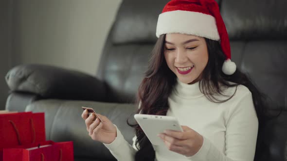 woman in santa hat shopping online for Christmas gift with digital tablet in the living room