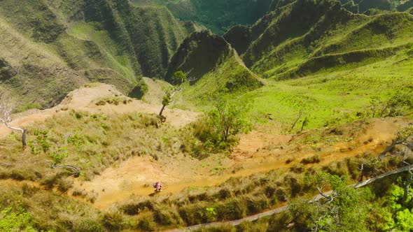 Aerial Epic Shot of Woman Hiking on the Edge of Green Jungle Mountain Landscape alt