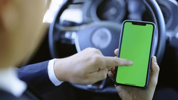 Man Hand Using Chromakey Mockup Mobile Phone With Empty Green Screen in Modern Car