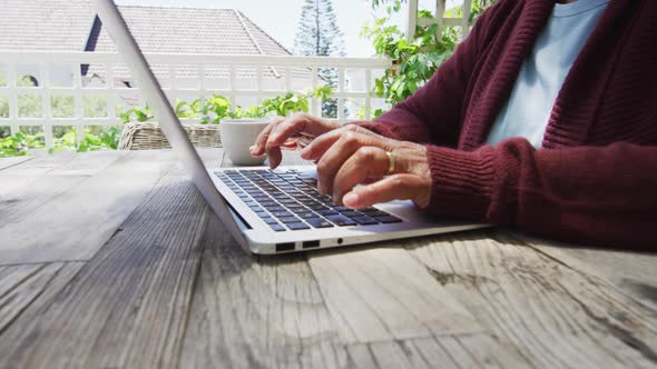 Midsection of senior mixed race woman using laptop outside alt