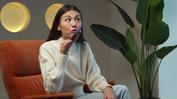 Asian Woman Using Mobile Phone Sound Recognition to Send a Message While Holding a Gadget to Her alt