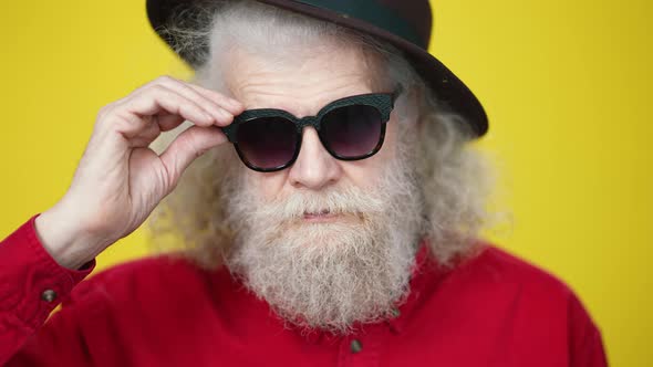 Headshot of Handsome Serious Senior Man Taking Off Sunglasses and Winking at Camera alt