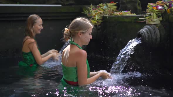 Slowmotion Shot of Two Young Women Visiting the Holly Springs in Indonesia. Tirta Empul Holy Water alt