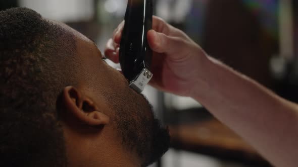 Professional Hairdresser Doing Beard Trim to Attractive Dark Skinned African American Guy alt