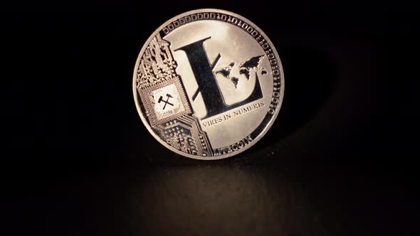 Shiny Litecoin LTC Rotating and Reflecting Light on a Wooden Surface