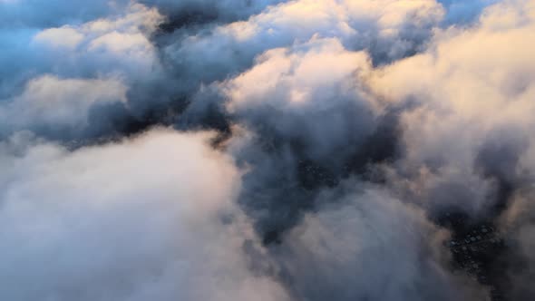 Aerial View From High Altitude of Distant City Covered with Puffy Cumulus Clouds Flying By Before alt